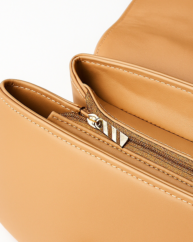 Close-up of a tan leather bag with a zipper on a white background
