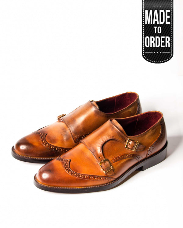A pair of brown double monk wingtip leather shoes with a visible label reading 'MADE TO ORDER'.