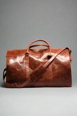 A brown premium top-grain leather duffle bag with dedicated compartments for suits, shoes, ties, and essentials, displayed in a flat position with the capacity to stand upright.