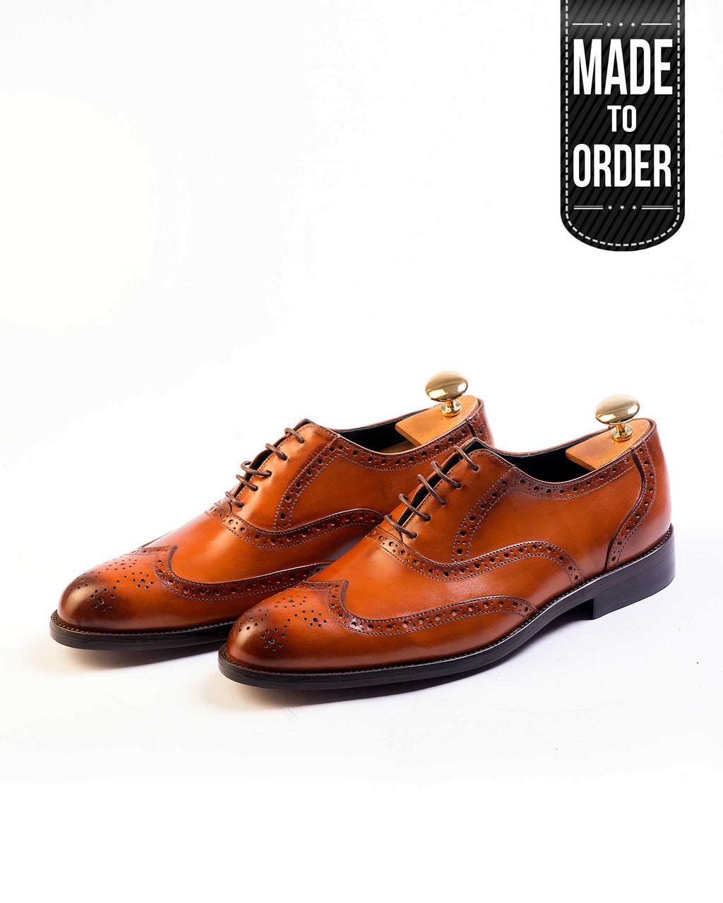A pair of tan, cordovan leather brogues with lace-up closure and a contrasting color sole.