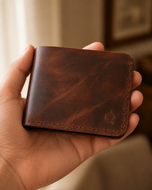 Bronco Crazy Horse leather bifold wallet held in hand, showing its compact front-pocket size