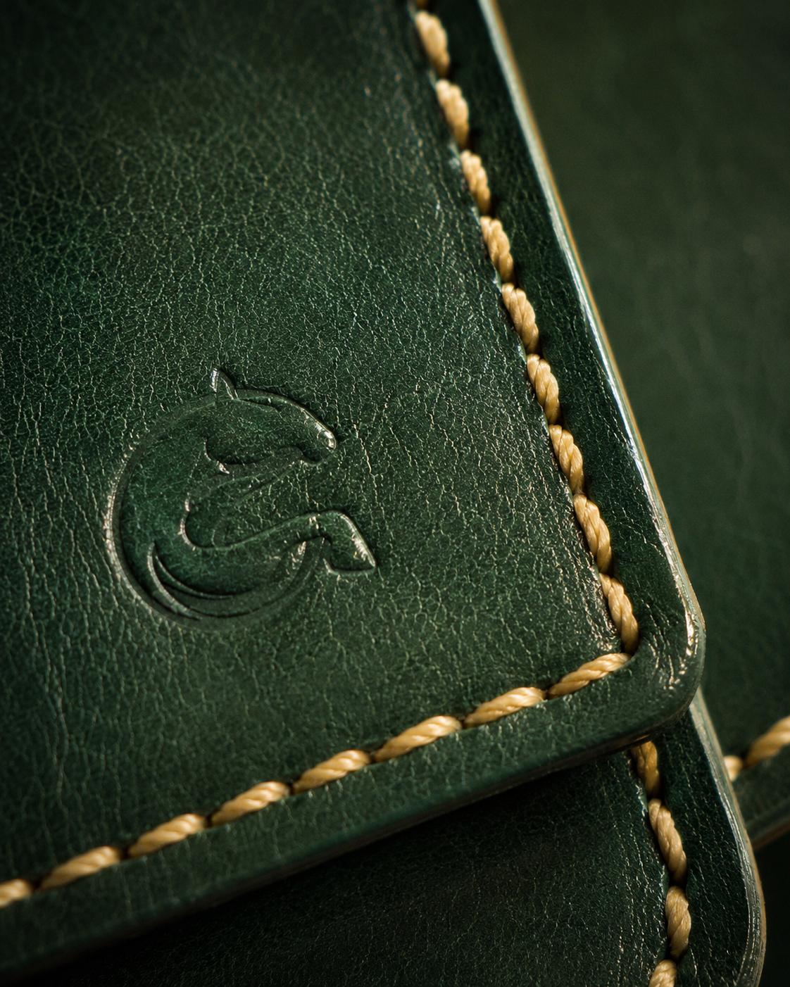 Close-up of the emerald full-grain leather grain and hand-stitching on the Cleopatra wallet