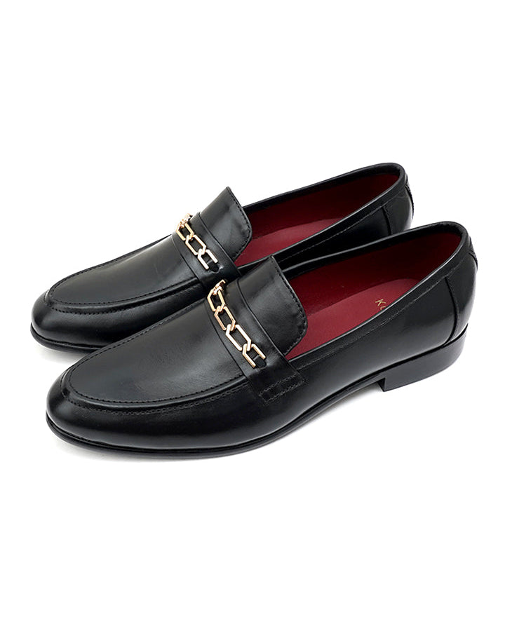 A pair of black Linker Moccasin shoes with distinctive chain embellishment on the front, displayed against a white background.