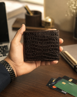 Brown Gator crocodile-textured leather wallet held in hand