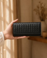 Black Nova woven leather clutch held in hand