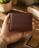 Tan nappa leather bifold wallet held in hand, showing slim profile