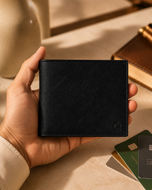 Midnight black saffiano leather bifold wallet held in hand for scale