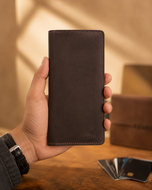 Dark brown Crazy Horse leather long wallet held in hand for scale