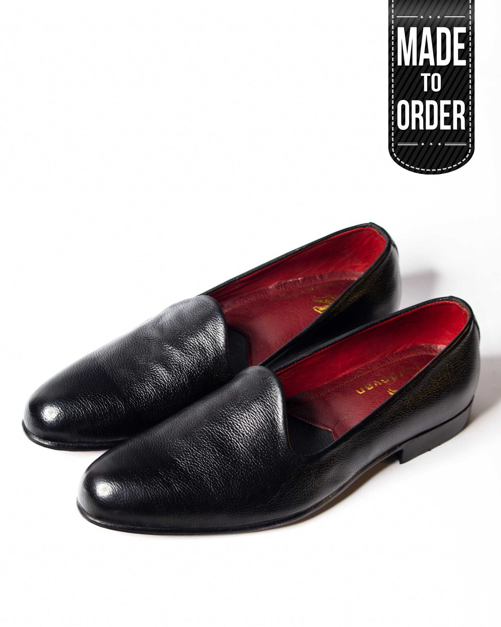 A pair of black, high-end open loafers with a red leather sole, displayed against a white background with a 'made to order' label.